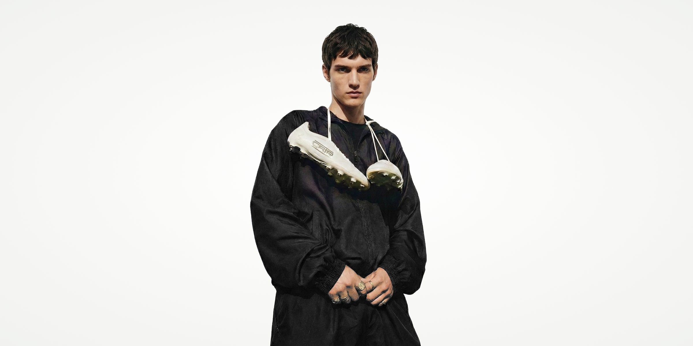 CRID model in a black tracksuit, a pair of football boots around his neck