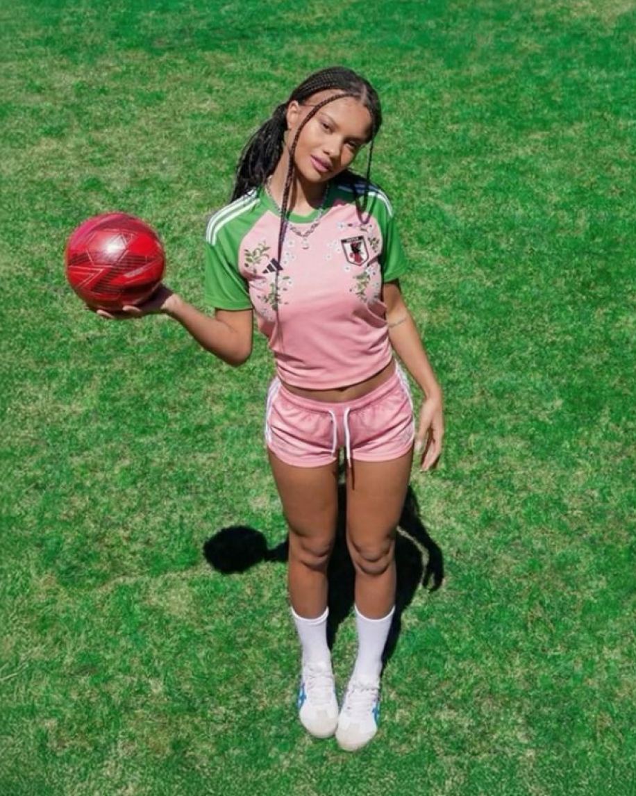 Player standing on a grass pitch, red ball in hand, seen from above